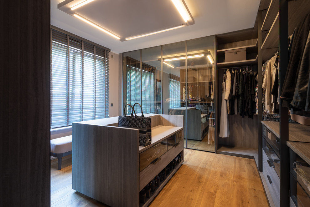Пример оригинального дизайна: гардеробная комната среднего размера в современном стиле с плоскими фасадами, деревянным полом и коричневым полом