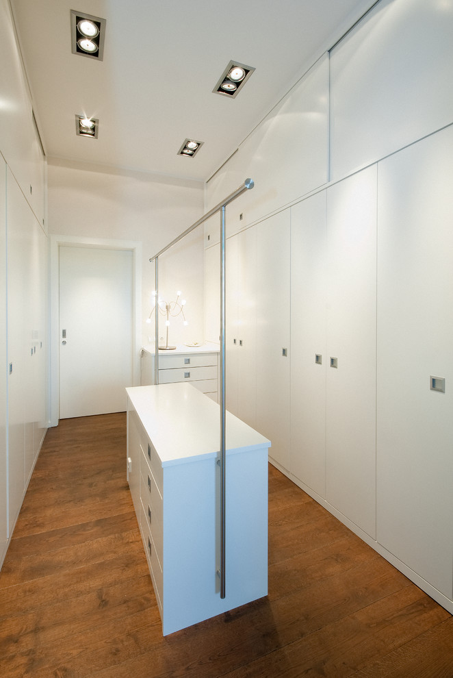 Mittelgroßes, Neutrales Modernes Ankleidezimmer mit Ankleidebereich, flächenbündigen Schrankfronten, weißen Schränken, braunem Holzboden und braunem Boden in Köln