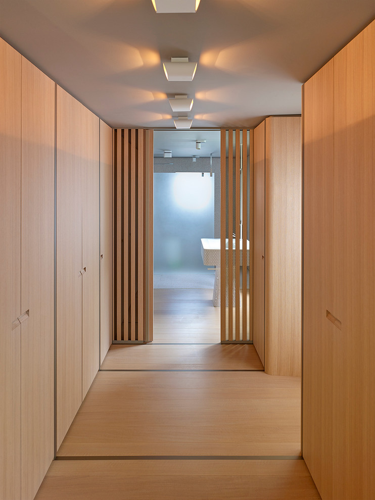 Idee per una grande cabina armadio unisex minimalista con ante lisce, pavimento in legno massello medio, pavimento beige e ante in legno chiaro
