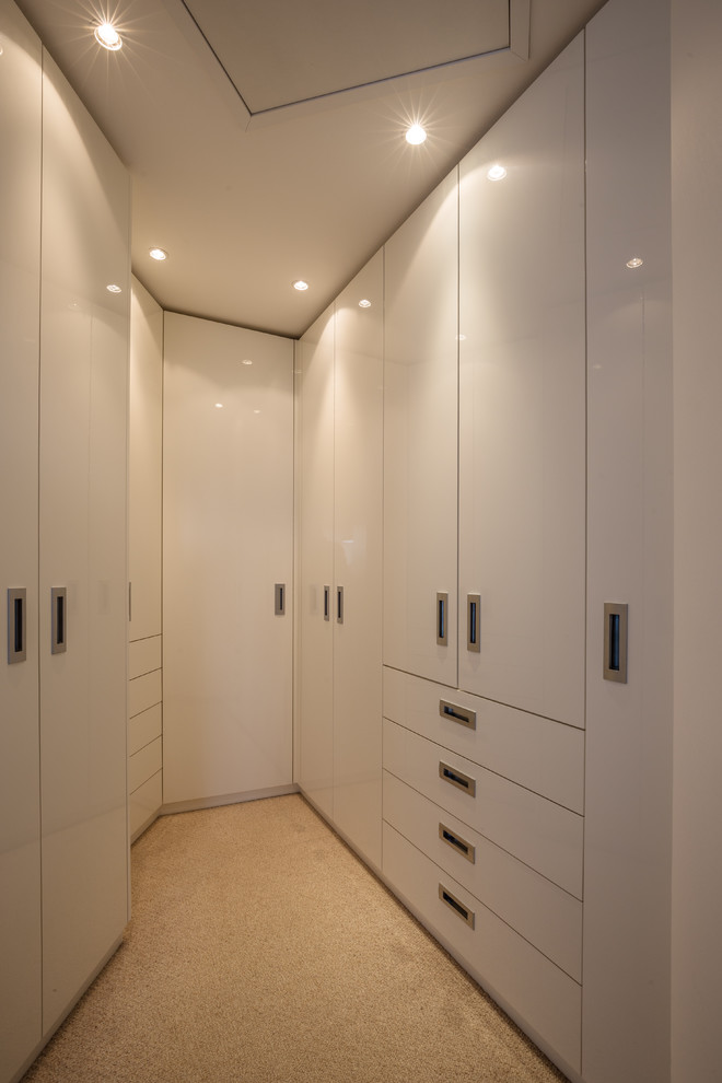 Esempio di una piccola cabina armadio unisex moderna con ante lisce, ante bianche, moquette e pavimento beige