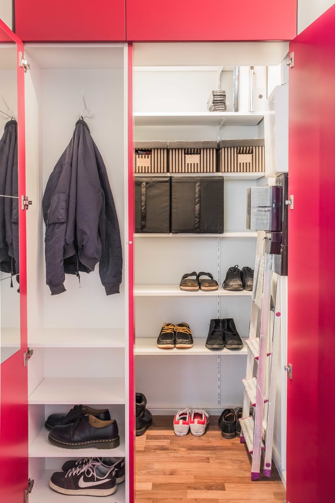 Minimalistisk inredning av ett litet walk-in-closet för könsneutrala, med släta luckor, röda skåp, mörkt trägolv och brunt golv