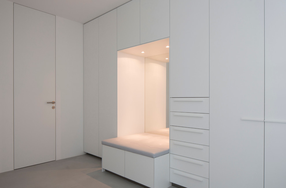Modelo de vestidor unisex actual de tamaño medio con armarios con paneles lisos, puertas de armario blancas y suelo de cemento