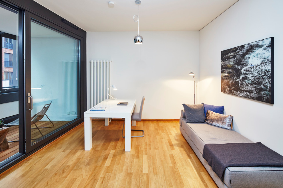 Foto de despacho contemporáneo de tamaño medio sin chimenea con paredes blancas, suelo de madera clara, escritorio independiente y suelo marrón