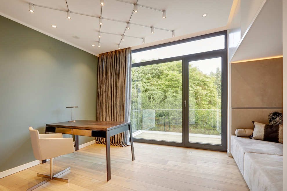 Mittelgroßes Modernes Arbeitszimmer ohne Kamin mit Arbeitsplatz, grüner Wandfarbe, hellem Holzboden, freistehendem Schreibtisch und beigem Boden in München