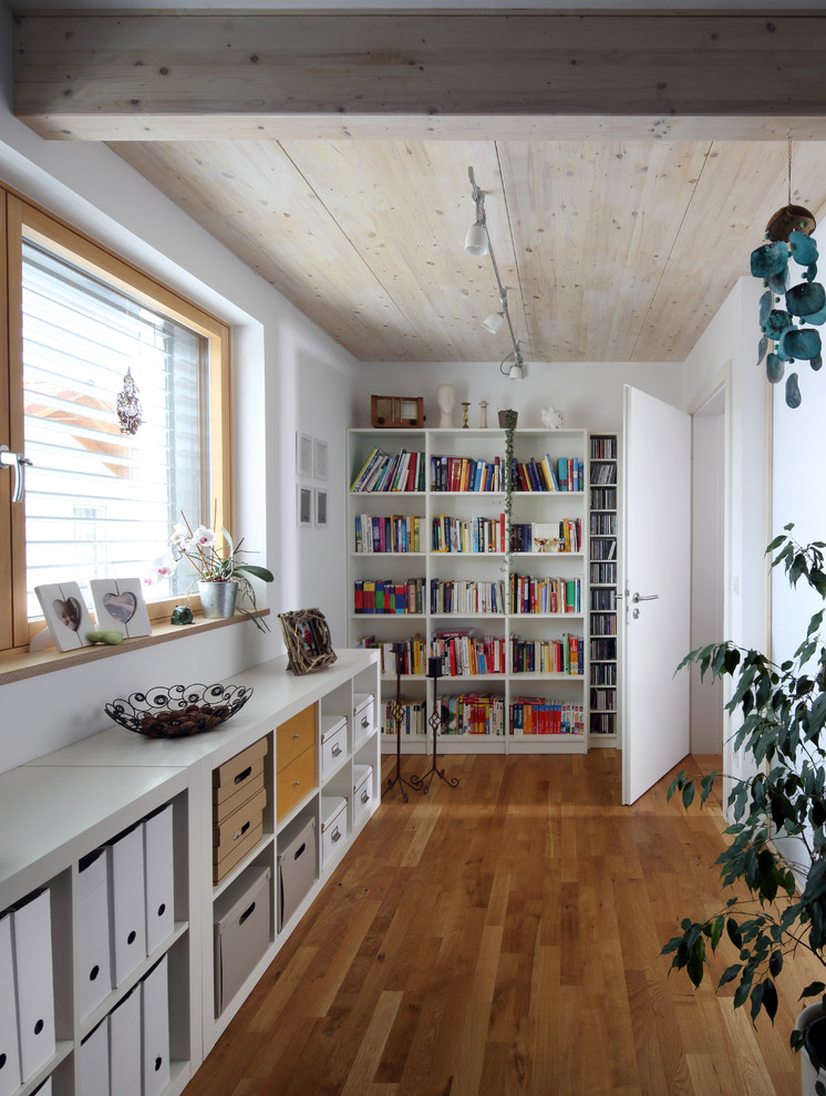 Inspiration för mellanstora moderna arbetsrum, med ett bibliotek, vita väggar, mellanmörkt trägolv och brunt golv