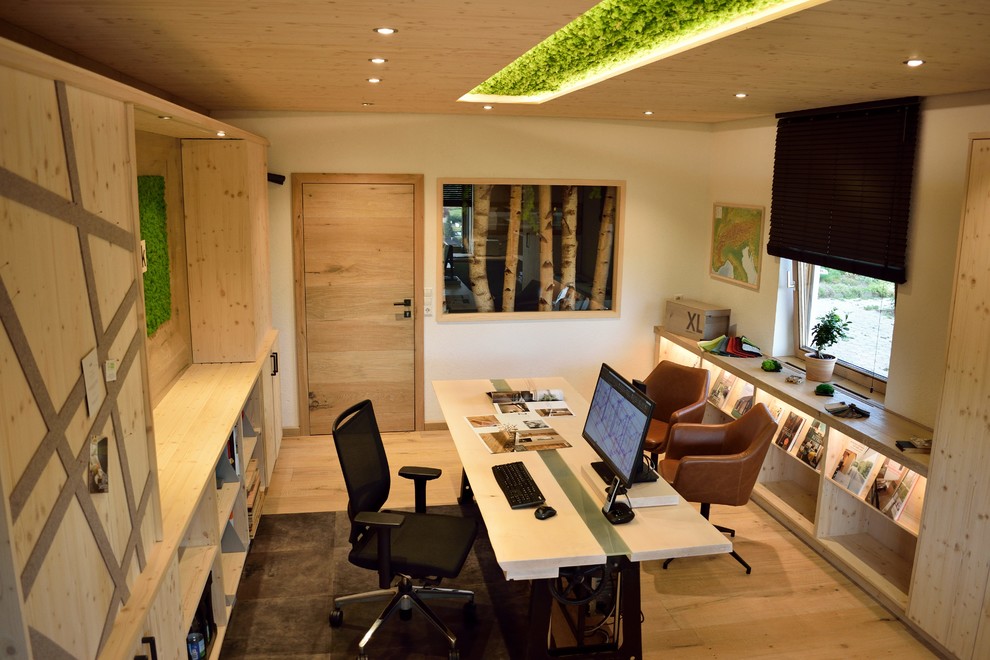 Mittelgroßes Modernes Arbeitszimmer mit Arbeitsplatz, weißer Wandfarbe, hellem Holzboden, freistehendem Schreibtisch und beigem Boden in Sonstige