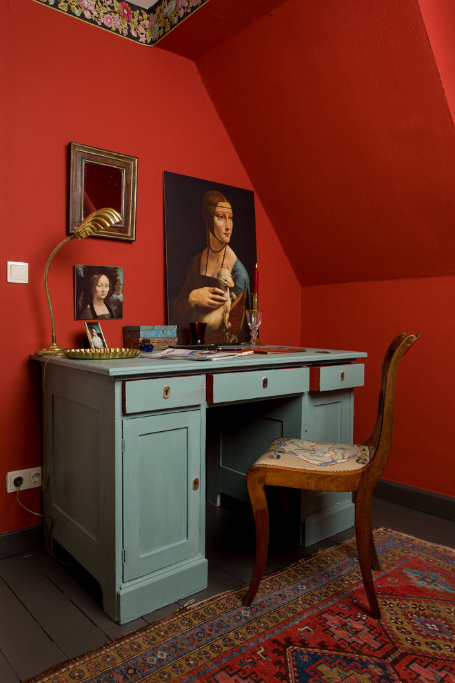 Imagen de despacho de estilo de casa de campo de tamaño medio con paredes rojas, suelo de madera oscura, escritorio independiente y suelo marrón