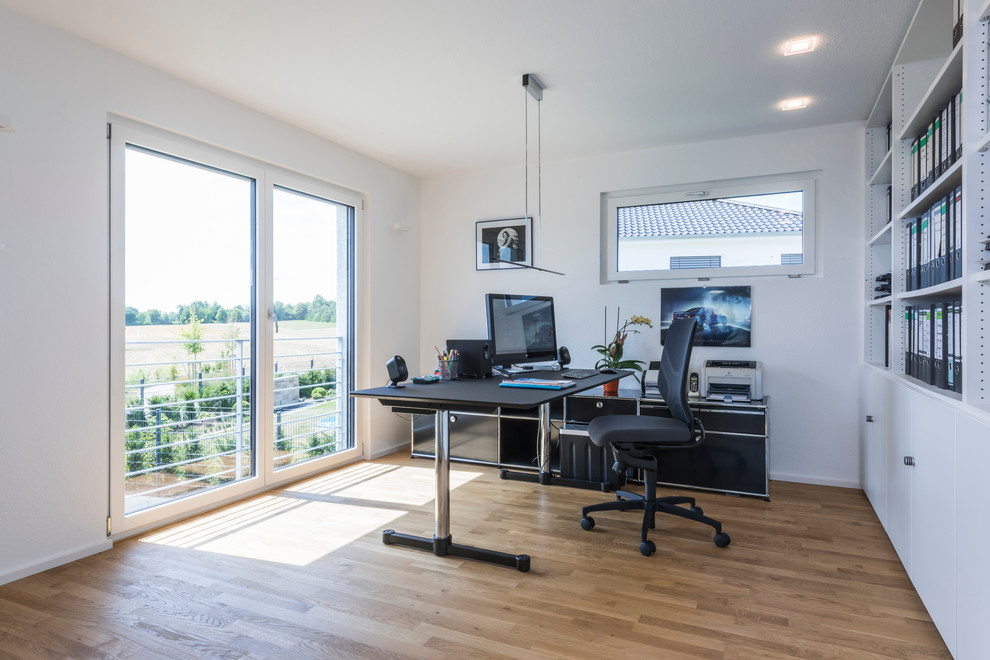 Mittelgroßes Modernes Arbeitszimmer mit weißer Wandfarbe, freistehendem Schreibtisch, Arbeitsplatz und hellem Holzboden in Sonstige