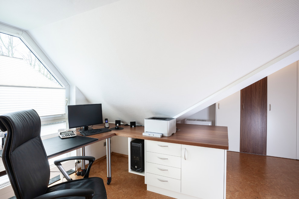 Idée de décoration pour un bureau design de taille moyenne avec un mur blanc, un sol en liège, un bureau intégré et un sol marron.