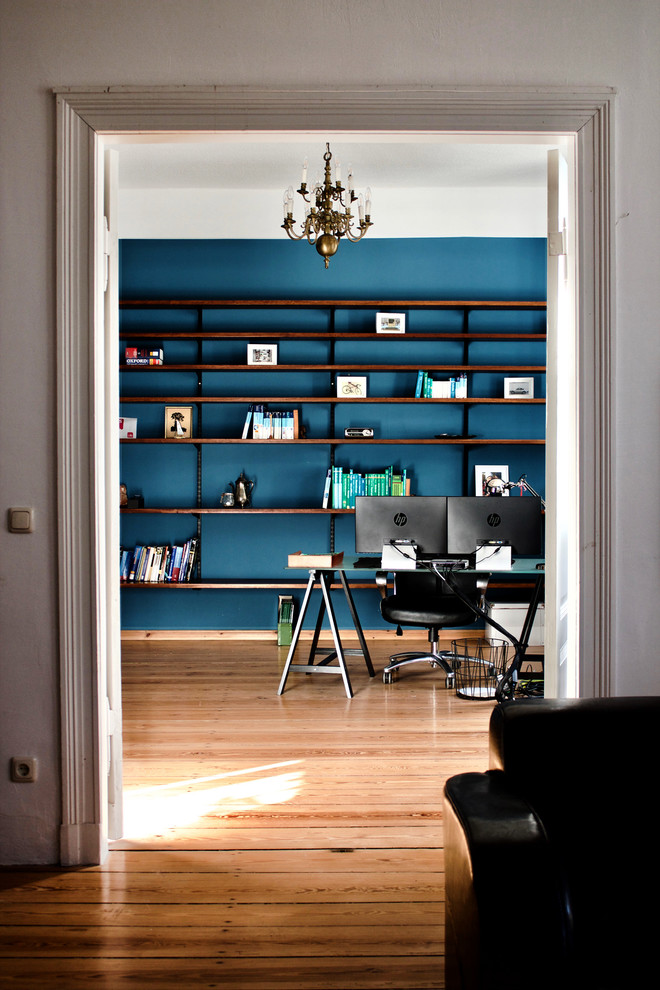 Idee per un grande studio minimalista con libreria, pareti blu, pavimento in legno massello medio, stufa a legna, cornice del camino piastrellata, scrivania autoportante e pavimento marrone