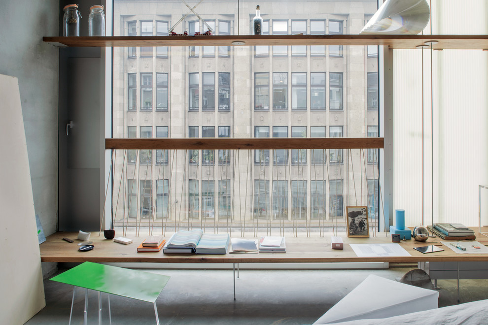 Ejemplo de despacho industrial con paredes grises, suelo de cemento y escritorio empotrado