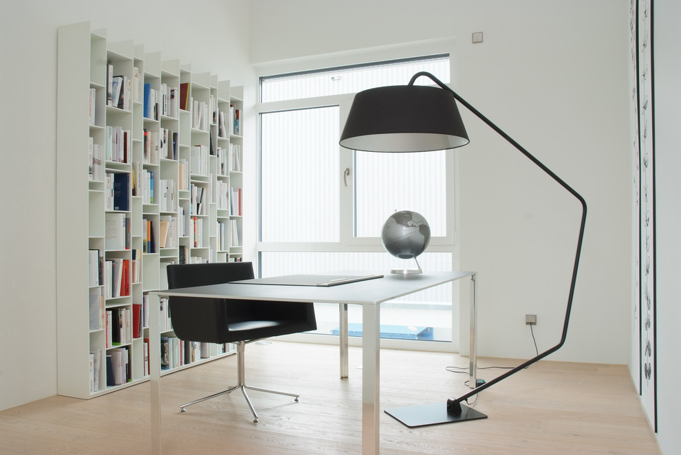 Mittelgroßes Modernes Arbeitszimmer ohne Kamin mit Arbeitsplatz, weißer Wandfarbe, hellem Holzboden, freistehendem Schreibtisch und braunem Boden in Stuttgart