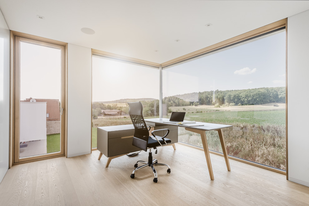 Aménagement d'un grand bureau moderne avec un mur blanc, parquet clair, un bureau indépendant et un sol beige.