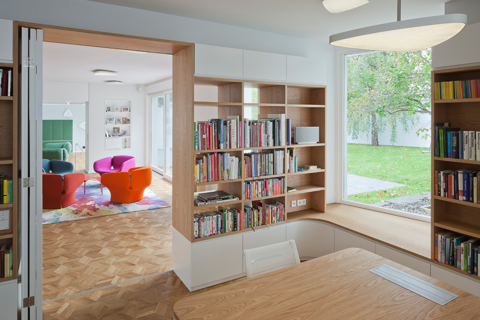 Exemple d'un bureau tendance de taille moyenne avec une bibliothèque ou un coin lecture, un mur blanc, un sol en bois brun, aucune cheminée, un bureau indépendant et un sol marron.