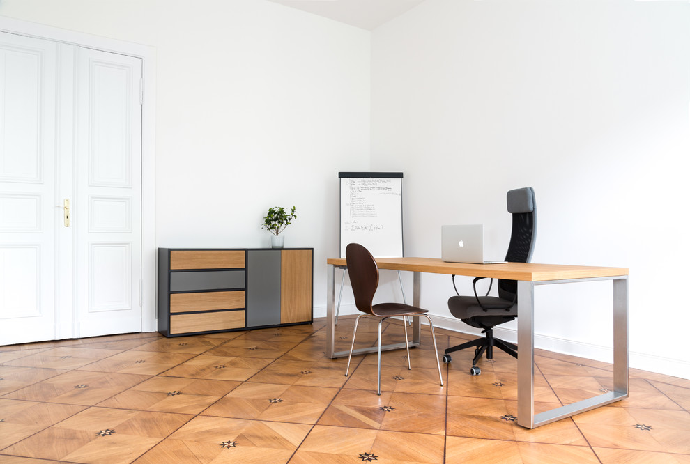Imagen de despacho urbano extra grande con paredes blancas, suelo de madera en tonos medios y escritorio independiente