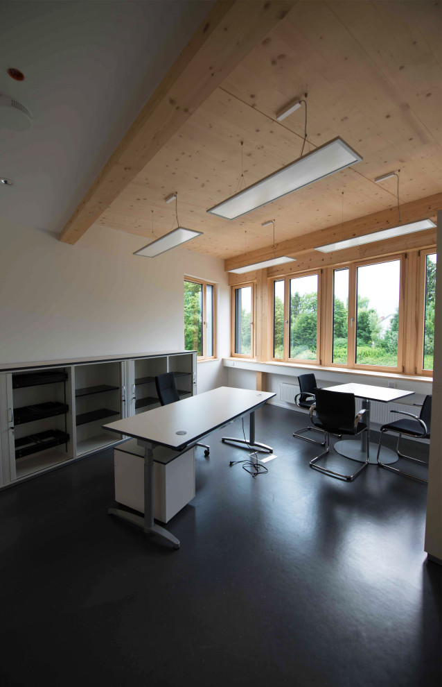Idee per un ufficio minimal di medie dimensioni con pareti bianche, pavimento in linoleum, scrivania autoportante e soffitto in legno