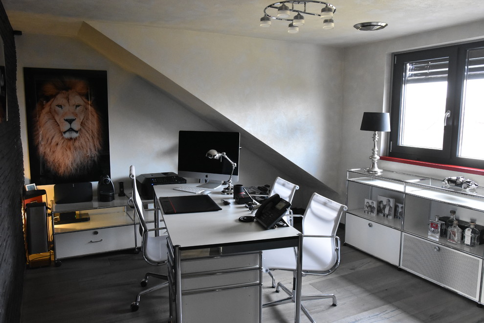 Modelo de despacho contemporáneo grande con escritorio independiente, paredes multicolor y suelo de madera en tonos medios