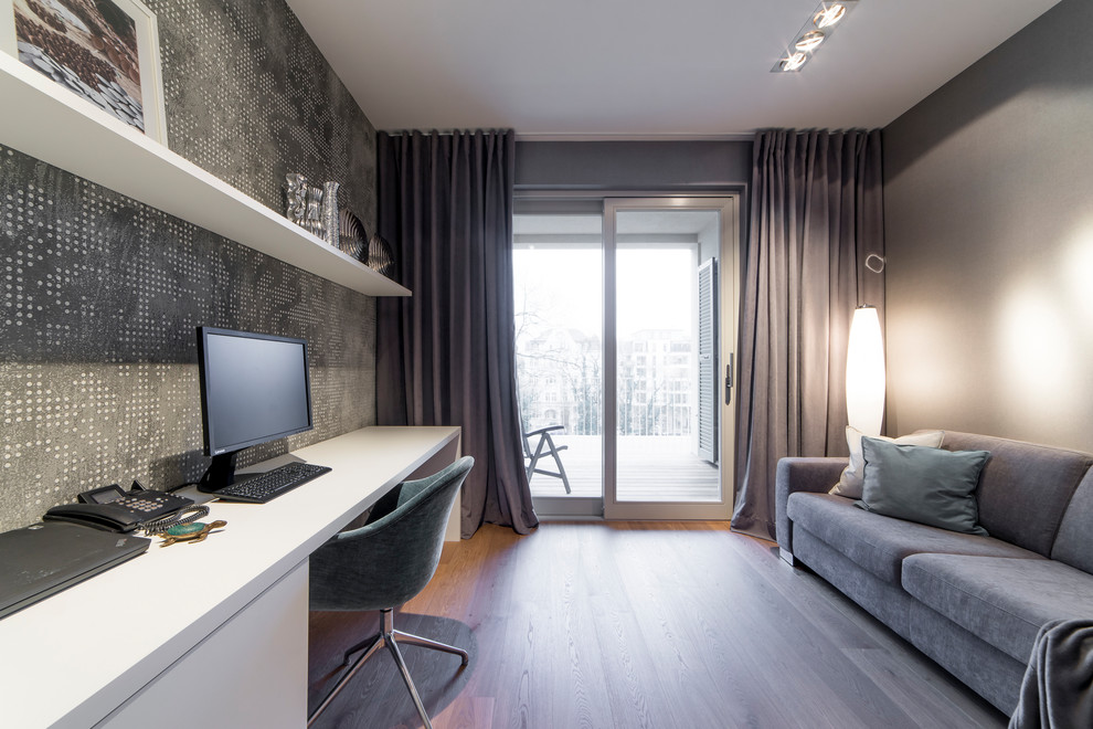 Mittelgroßes Modernes Arbeitszimmer mit Arbeitsplatz, grauer Wandfarbe, braunem Holzboden, Einbau-Schreibtisch und braunem Boden in Leipzig