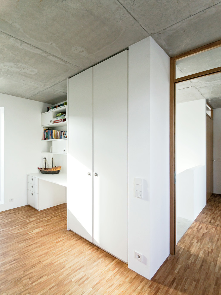 Immagine di un piccolo ufficio minimalista con pareti bianche, pavimento in legno massello medio, scrivania incassata e pavimento marrone