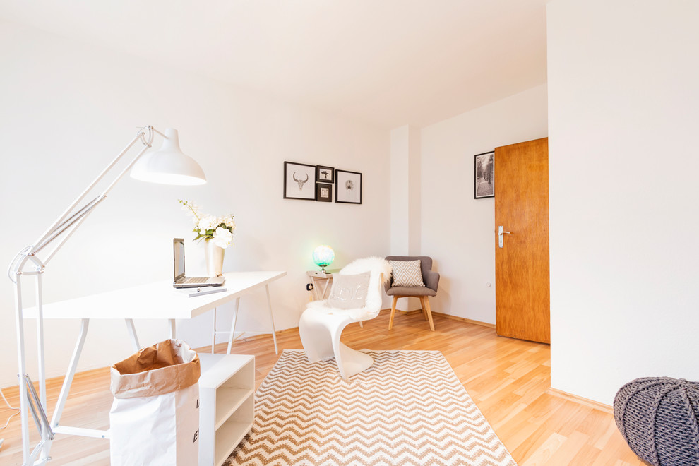 Modelo de despacho contemporáneo de tamaño medio sin chimenea con paredes blancas, suelo de madera en tonos medios, escritorio independiente y suelo beige