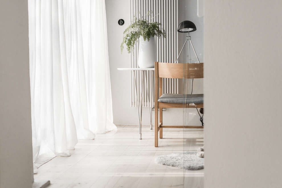 Пример оригинального дизайна: маленькое рабочее место в скандинавском стиле с белыми стенами, встроенным рабочим столом и светлым паркетным полом для на участке и в саду