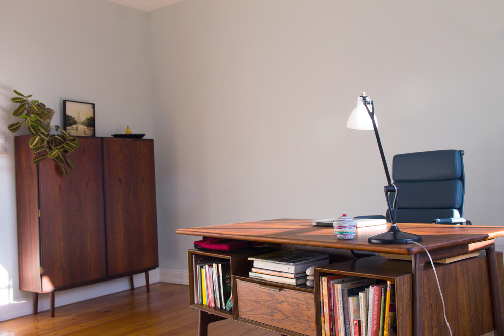 Medium sized modern study in Hamburg with green walls, light hardwood flooring and a freestanding desk.