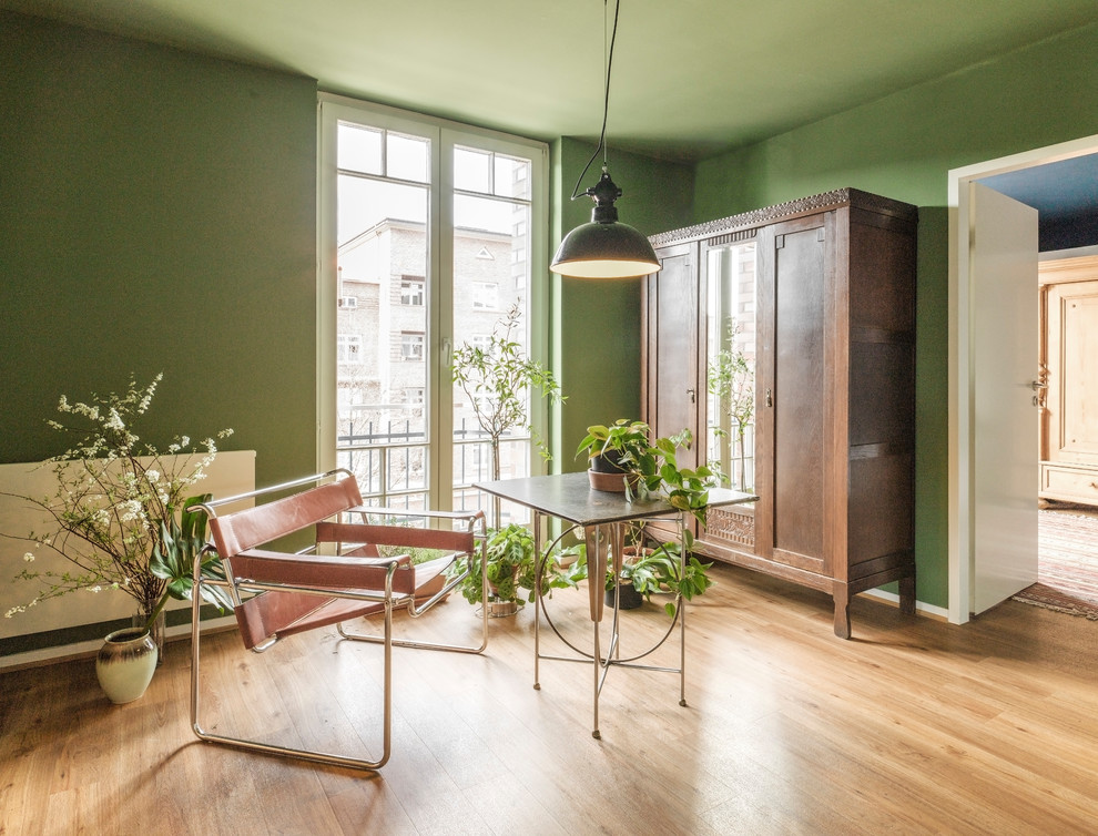 Mittelgroßes Eklektisches Arbeitszimmer ohne Kamin mit Arbeitsplatz, grüner Wandfarbe, braunem Holzboden, freistehendem Schreibtisch und braunem Boden in Hamburg