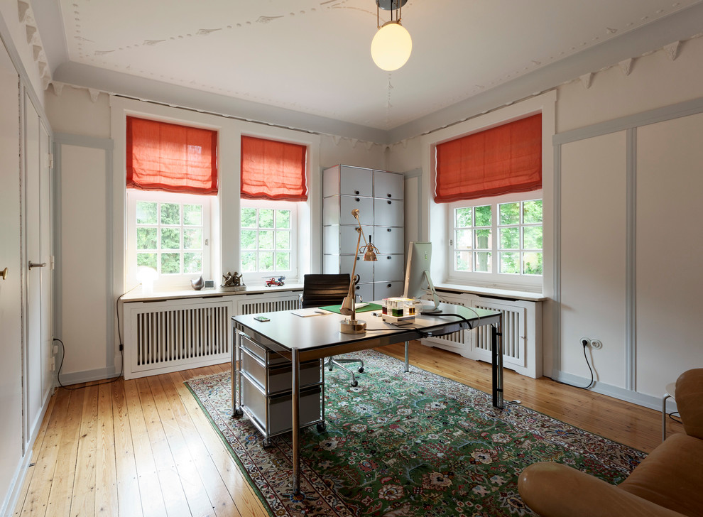 Mittelgroßes Modernes Arbeitszimmer ohne Kamin mit Arbeitsplatz, weißer Wandfarbe, braunem Holzboden und freistehendem Schreibtisch in Hamburg