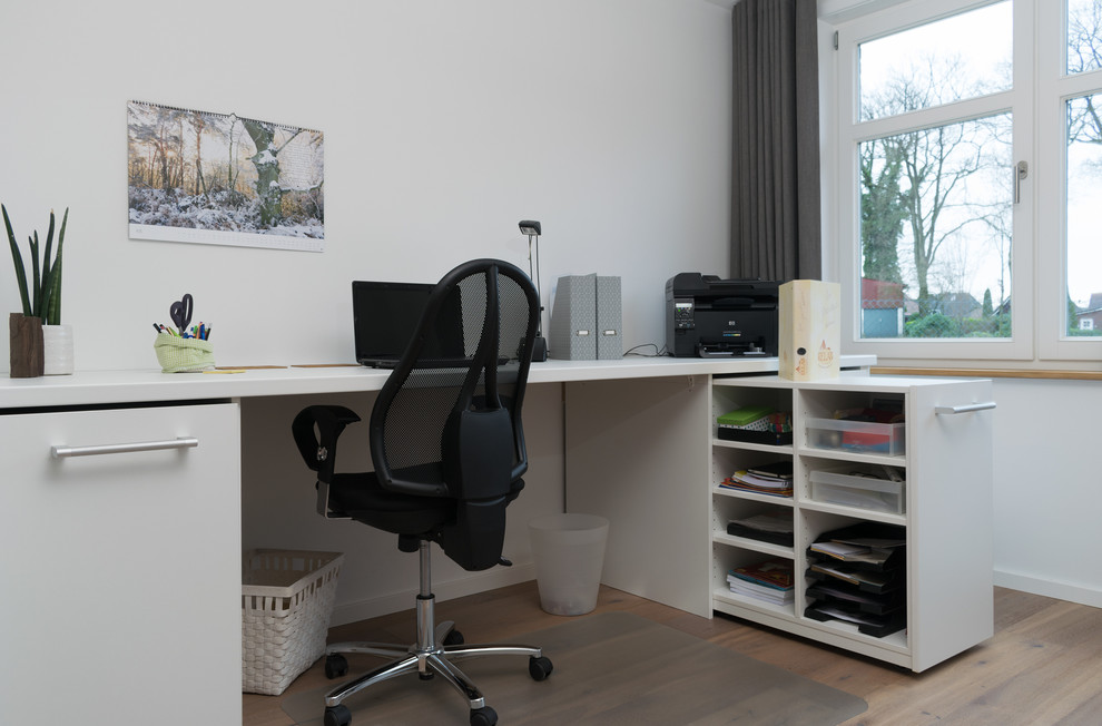 Mittelgroßes Modernes Arbeitszimmer ohne Kamin mit Arbeitsplatz, braunem Boden, weißer Wandfarbe, braunem Holzboden und Einbau-Schreibtisch in Hamburg