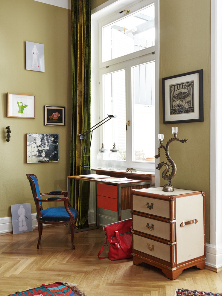 Inspiration för ett eklektiskt hemmabibliotek, med ett fristående skrivbord, gröna väggar och mellanmörkt trägolv