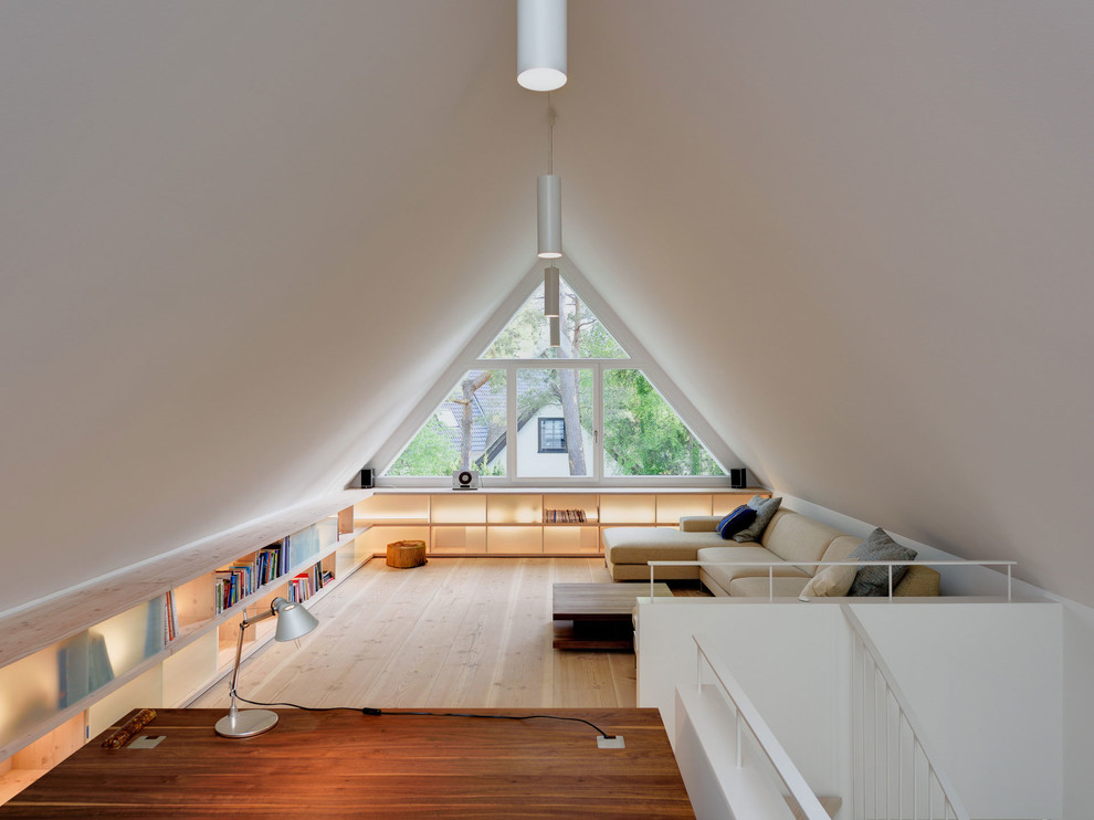 Ejemplo de despacho actual de tamaño medio sin chimenea con paredes blancas, suelo de madera clara y escritorio independiente