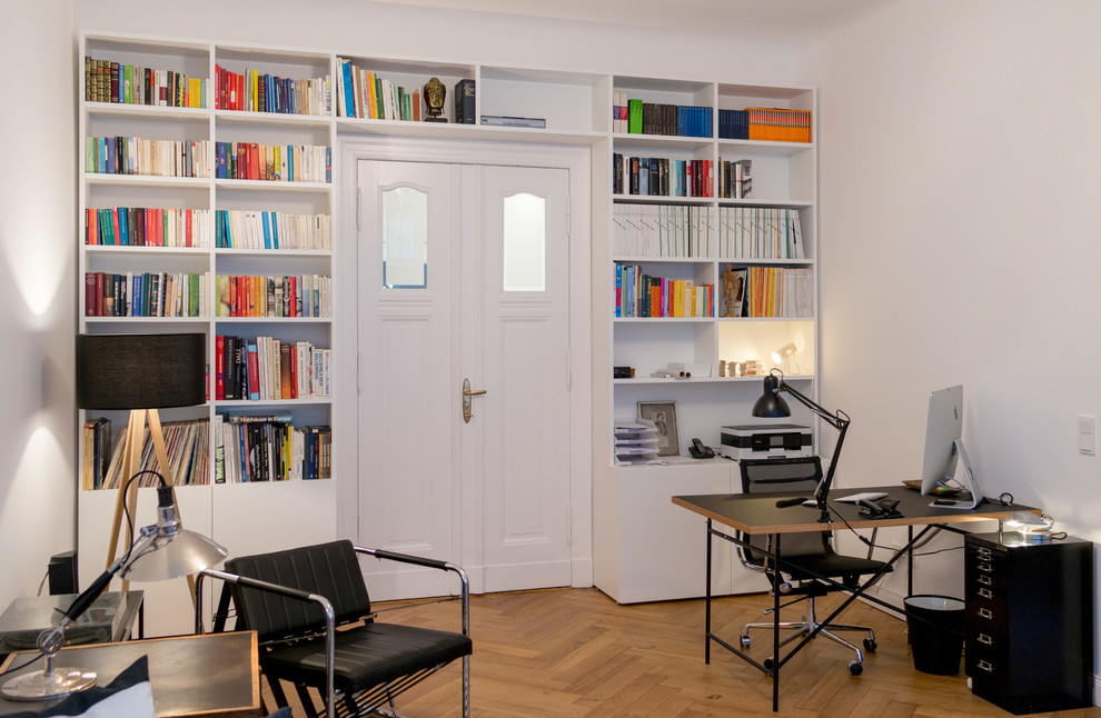 Geräumiges Modernes Lesezimmer ohne Kamin mit weißer Wandfarbe, braunem Holzboden, freistehendem Schreibtisch und beigem Boden in Berlin