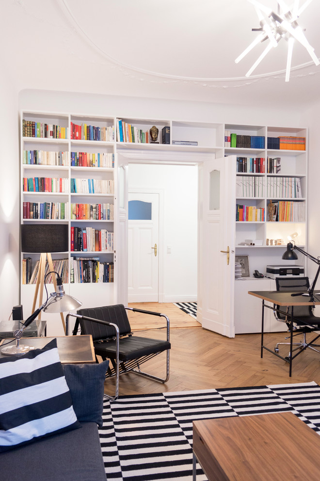 Immagine di un ampio studio design con libreria, pareti bianche, pavimento in legno massello medio, nessun camino, scrivania autoportante e pavimento beige