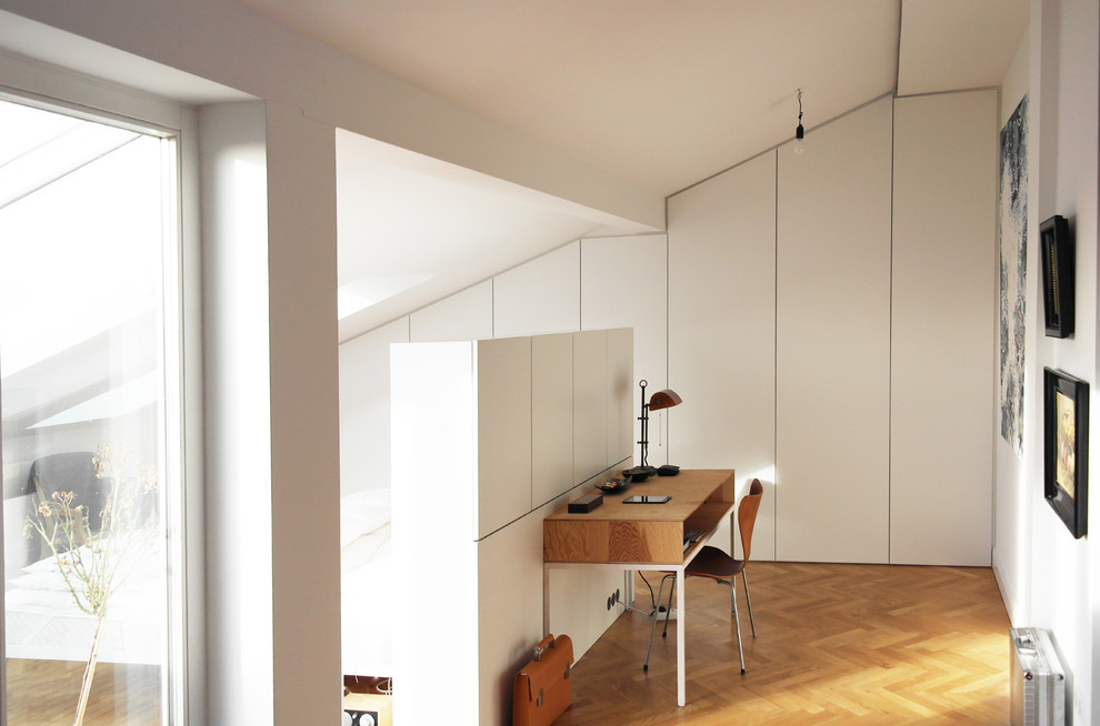 Cette image montre un bureau nordique de taille moyenne avec un mur blanc, un sol en bois brun, aucune cheminée, un sol marron et un bureau indépendant.