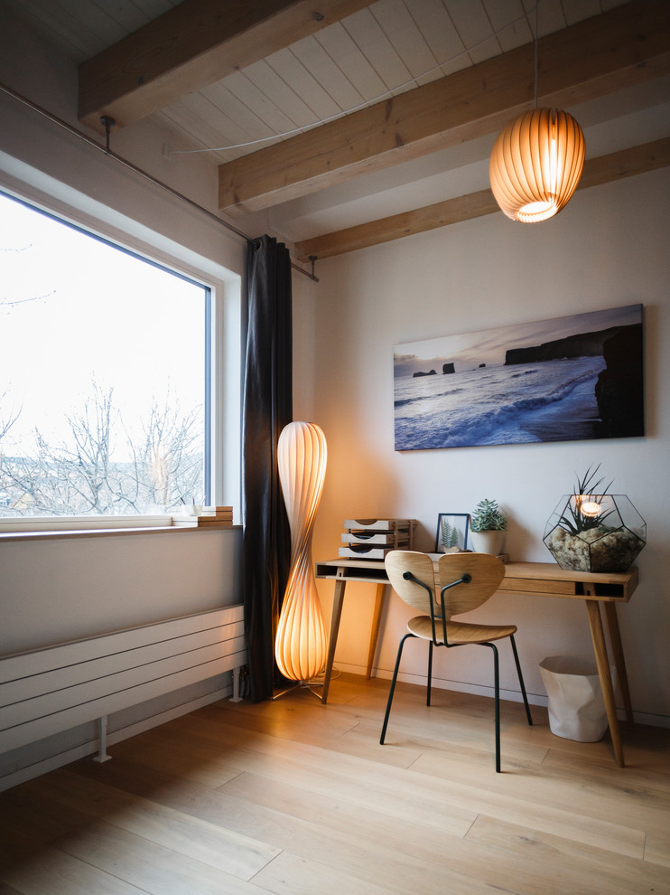 Mittelgroßes Skandinavisches Arbeitszimmer ohne Kamin mit Arbeitsplatz, weißer Wandfarbe, hellem Holzboden, freistehendem Schreibtisch und braunem Boden in Berlin