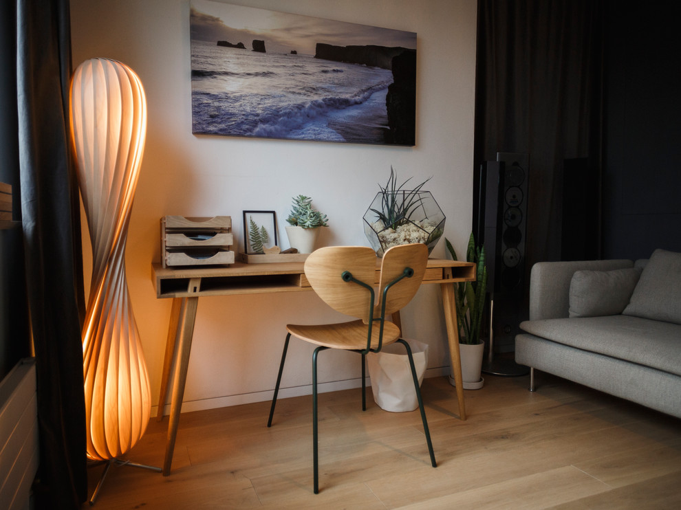 Modelo de despacho escandinavo pequeño sin chimenea con paredes blancas, suelo de madera en tonos medios, escritorio independiente y suelo marrón