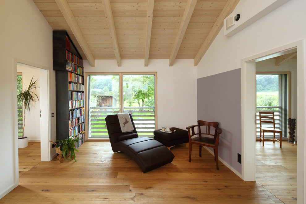 Kleines Modernes Lesezimmer ohne Kamin mit dunklem Holzboden, weißer Wandfarbe und braunem Boden in München