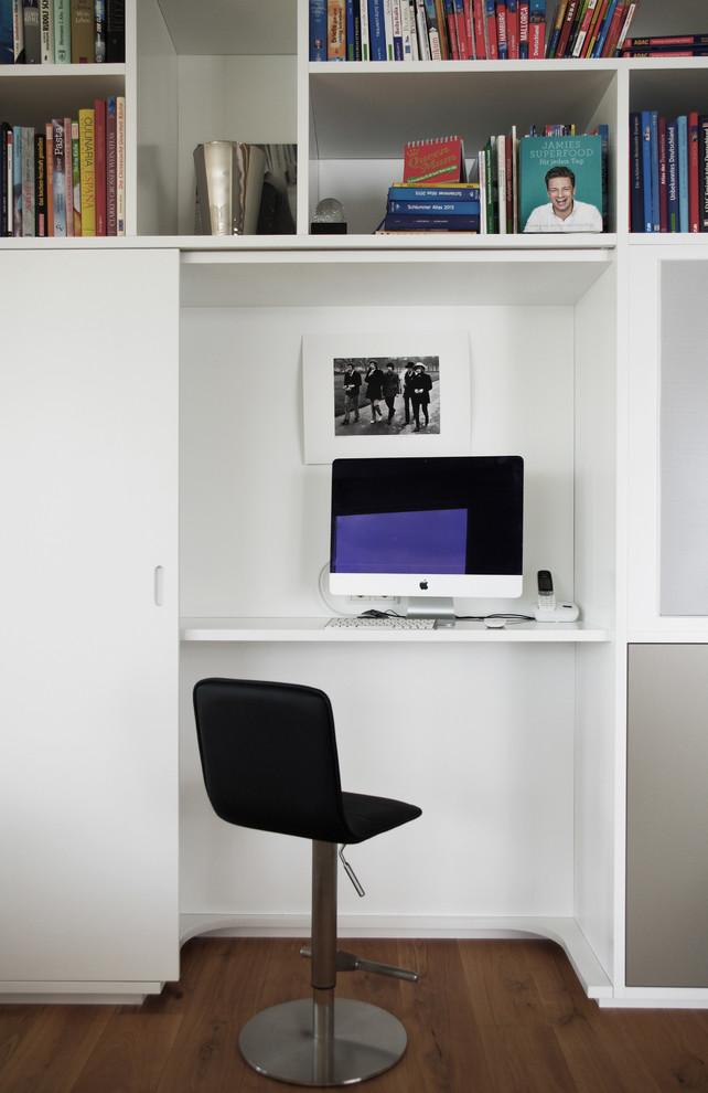 Kleines Modernes Arbeitszimmer mit Arbeitsplatz, weißer Wandfarbe, dunklem Holzboden und Einbau-Schreibtisch in Sonstige