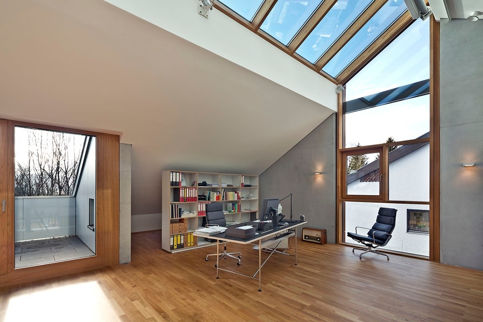 Großes Modernes Arbeitszimmer ohne Kamin mit Arbeitsplatz, grauer Wandfarbe, hellem Holzboden und freistehendem Schreibtisch in Stuttgart