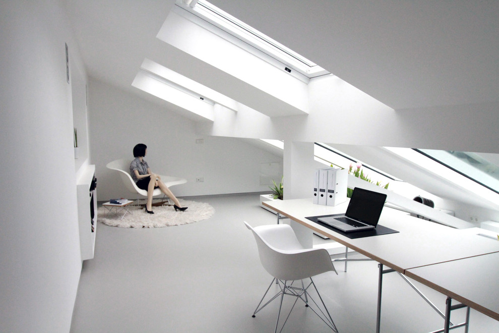 Modern inredning av ett arbetsrum, med vita väggar, linoleumgolv, ett fristående skrivbord och grått golv