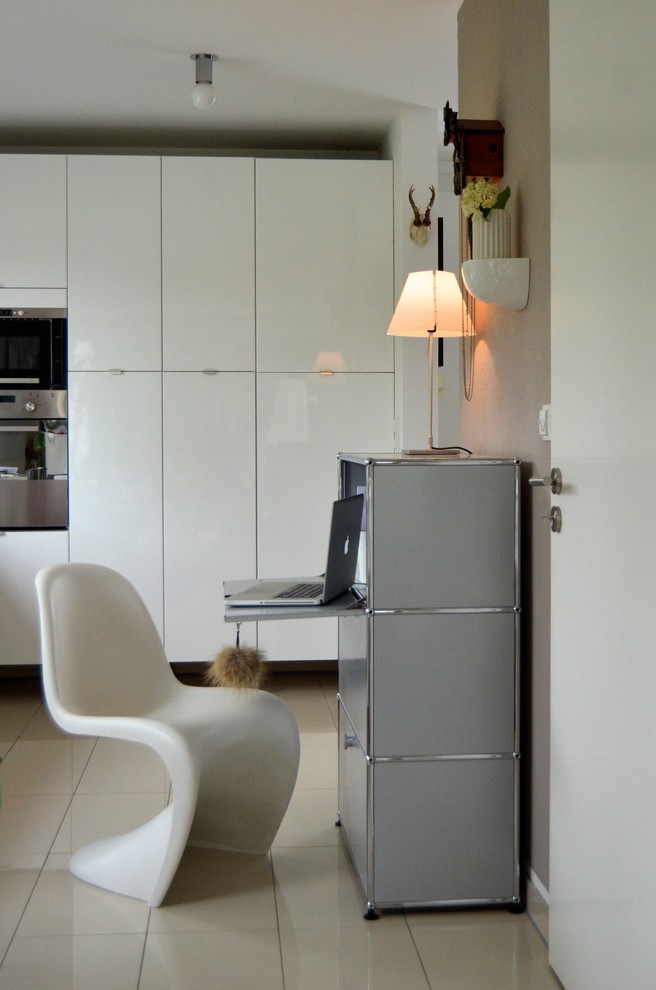 Modelo de despacho contemporáneo pequeño sin chimenea con suelo de baldosas de cerámica, escritorio independiente y paredes beige