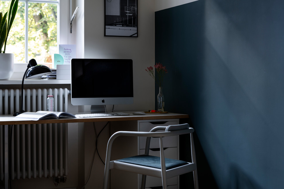 Kleines Modernes Arbeitszimmer mit Arbeitsplatz, blauer Wandfarbe und freistehendem Schreibtisch in Berlin