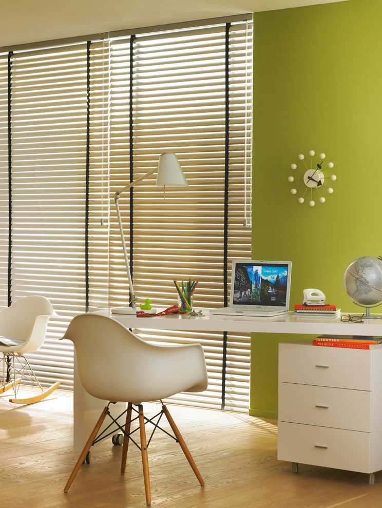 Modernes Arbeitszimmer ohne Kamin mit Arbeitsplatz, grüner Wandfarbe, braunem Holzboden und freistehendem Schreibtisch in Hamburg
