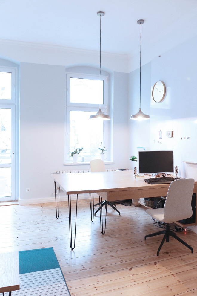 Diseño de despacho actual grande con paredes azules, suelo de madera clara y escritorio empotrado
