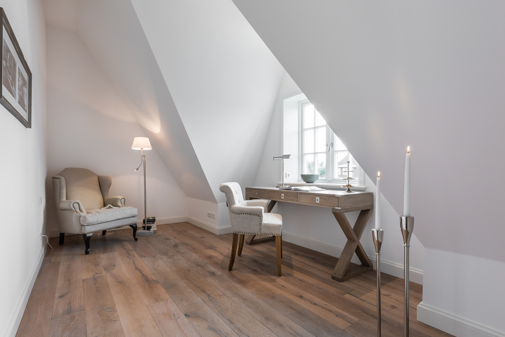 Mittelgroßes Landhausstil Arbeitszimmer ohne Kamin mit Arbeitsplatz, weißer Wandfarbe, braunem Holzboden und freistehendem Schreibtisch in Sonstige