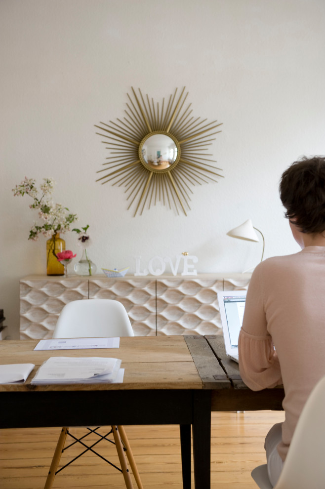 Photo of a study in Berlin with white walls, light hardwood flooring and a freestanding desk.