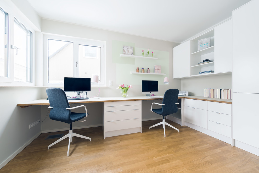 Diseño de despacho escandinavo de tamaño medio sin chimenea con paredes beige, suelo de madera en tonos medios, escritorio empotrado y suelo marrón