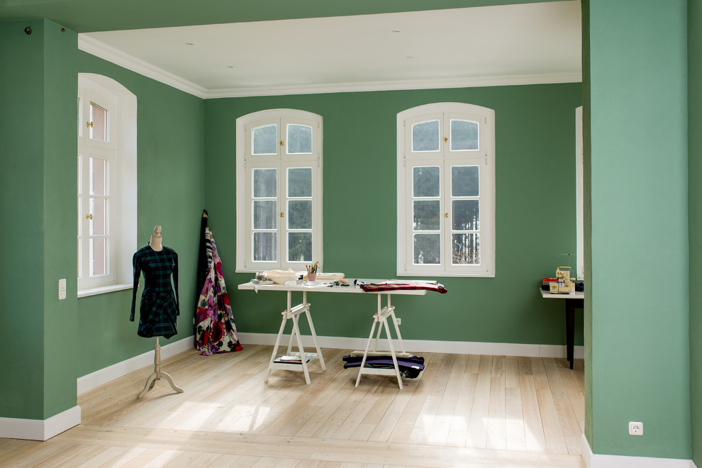 Diseño de sala de manualidades contemporánea grande con suelo de madera clara, escritorio independiente y suelo marrón