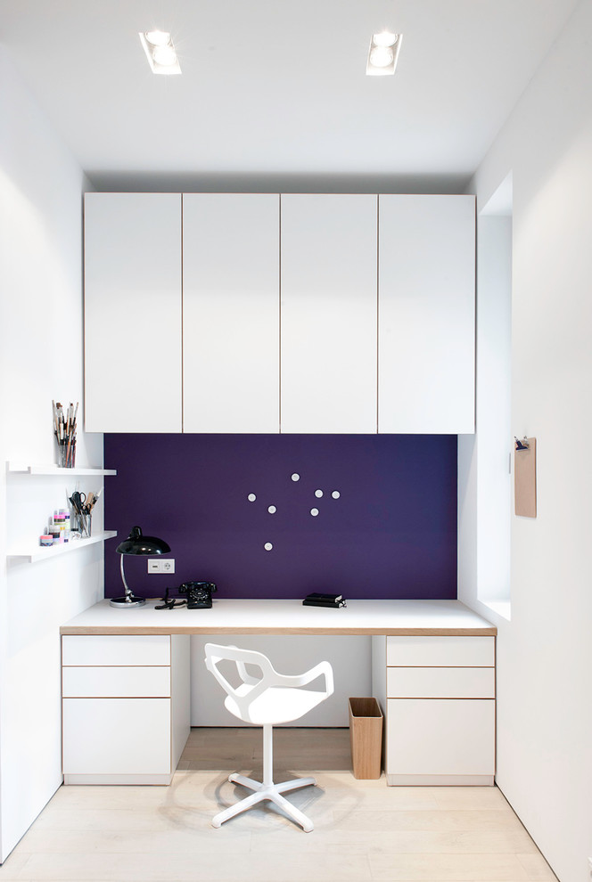 This is an example of a medium sized scandi study in Hamburg with light hardwood flooring, a built-in desk, purple walls and no fireplace.