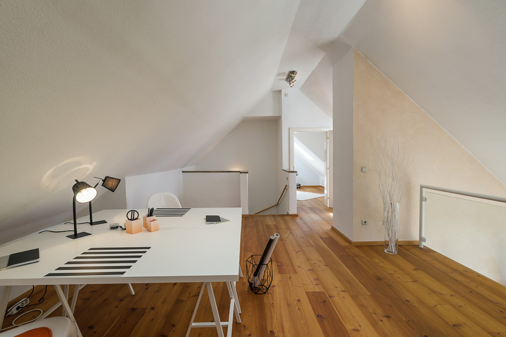 Mittelgroßes Klassisches Arbeitszimmer mit Arbeitsplatz, weißer Wandfarbe, braunem Holzboden, freistehendem Schreibtisch und braunem Boden in München